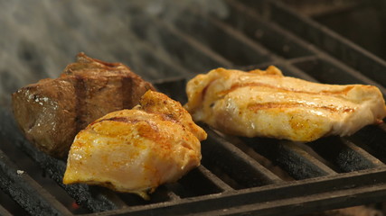 Meat grilled marinated in spices, turmeric, pepper, salt, two chicken fillets or turkey meat with grill prints and veal meat is medalled grilled, the tubers of smoke are torn from under the pieces of