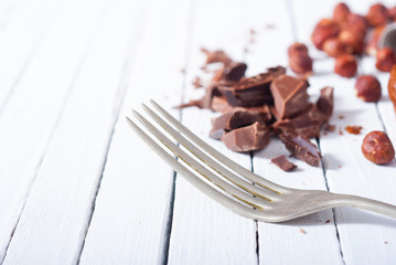 broken chocolate muffin and hazelnuts, fork on white wood table