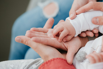 Mom and Dad hold baby's hand. Children's handle