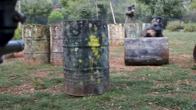 Paintball players aiming and shooting with guns at opposing team outdoors 