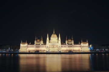 Fototapeta na wymiar Illuminated Budapest parliament building at night with dark sky and reflection in Danube river 
