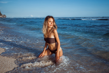 Fototapeta na wymiar Girl sitting on her knees on the beach in the water
