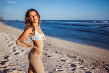 Fototapeta na wymiar Girl in a swimsuit in the sand is on the beach