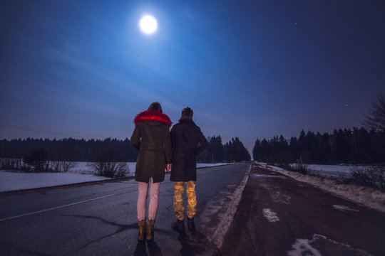 Young Couple Watching Beautiful Starry Sky On Full Moon Night.