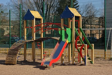 playground with colored slide and wooden buildings on the street