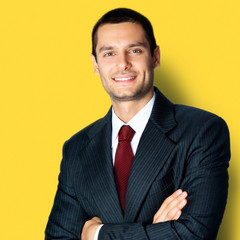 Happy businessman with crossed arms, on yellow