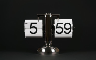 Isolated vintage flip clock on black background at five o'clock and fifty nine minutes