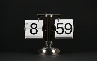 Isolated vintage flip clock on black background at eight o'clock and fifty nine minutes
