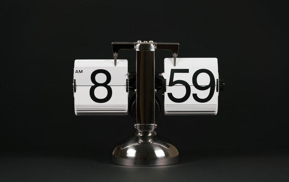 Isolated vintage flip clock on black background at eight o'clock and fifty nine minutes