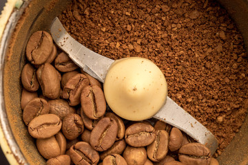 Macro photo of freshly ground coffee in electric coffee grinder with roasted coffee beans inside and coffee grains close-up view of the top.