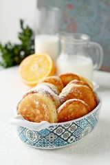 Yeast pancakes in powdered sugar with milk and honey on a light background. Yeast fritters for Sunday breakfast