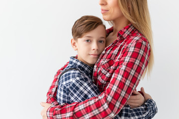 Mothers day, children and family concept - teen boy hugging his mom on white background