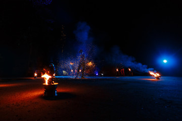 Fire show, dancing with flame, male master juggling with fireworks, performance outdoors, draws a fiery figure in the dark, bright sparks in the night.
