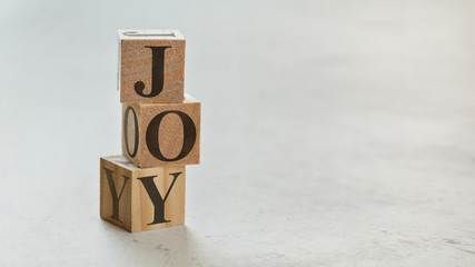 Pile with three wooden cubes - letters JOY on them, space for more text / images on right side.