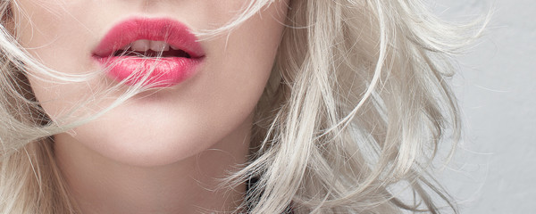 Close-up red plump lips of a young blonde woman on a white background. Cosmetology and plastic...