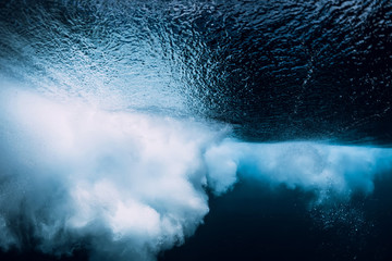 Underwater wave with foam. Blue powerful wave in ocean.
