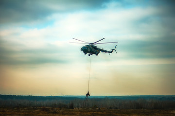Fototapeta na wymiar military army helicopter transporting an artillery piece.