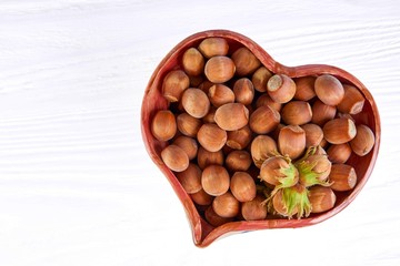 Hazelnuts in a heart vase isolated on white background