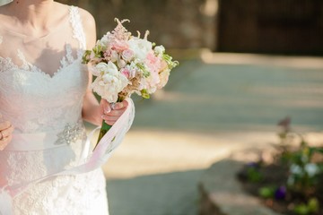 Wedding bouquet of delicate roses in the hands of the bride