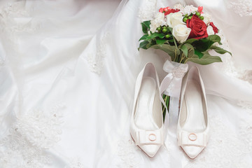 Obraz na płótnie Canvas Wedding bouquet on a dress of the bride with shoes and rings