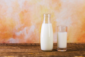 Glass and Bottle of fresh milk. Bottle with milk and glass of milk on wooden table.