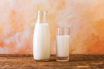 Glass and Bottle of fresh milk. Bottle with milk and glass of milk on wooden table.