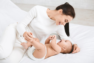Mother playing with her baby in bedroom.