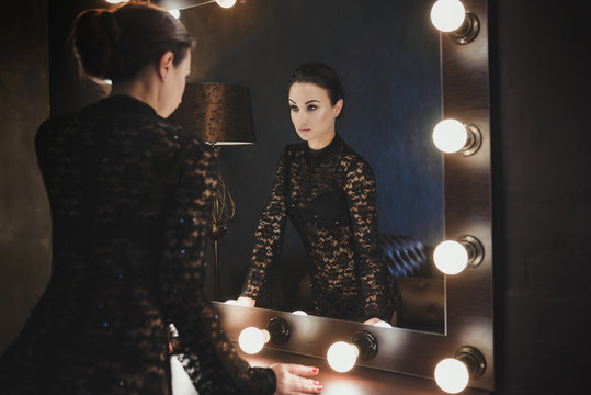 Elegant woman in dressing room looking into the large mirror