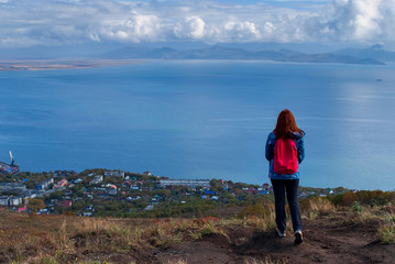 girl traveler on the edge of the cliff looking at the Bay and the ocean, the cold Pacific ocean, clouds