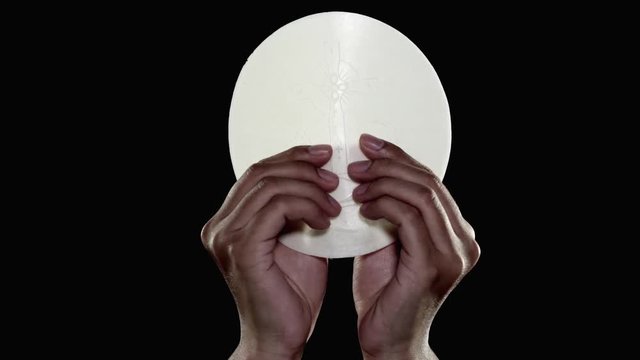 Pastor hands dividing a sacramental bread or communion bread on dark background. Shot in 4k resolution
