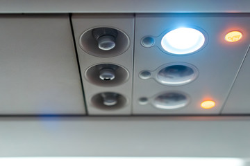 closeup airplane Console panel; lamp, light, need help button, air condition, sefty belt and no smoking lighting sign.