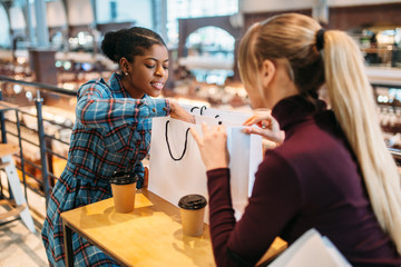 Two ladies drinks coffee in food-court, shopping