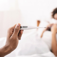 Fever 102 F, thermometer in black male hands