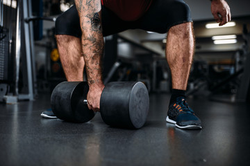 Male person with dumbbell, training in gym
