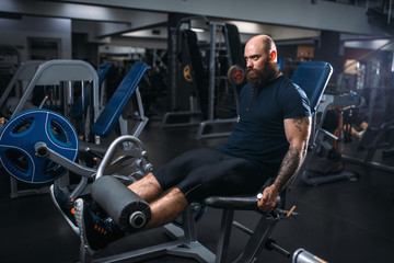 Muscular athlete trains legs on exercise machine