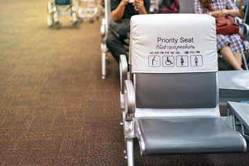 Obraz premium White and grey piority seat near gateway in the airport, with blur passengers behind. (Thai and Chinese language means 