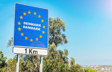 Road sign on the border of a European Union country, Denmark 1km ahead with blue sky copy space