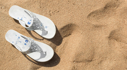 Fototapeta na wymiar Beach slippers on the sand at sea beach. Top view. Space for text.