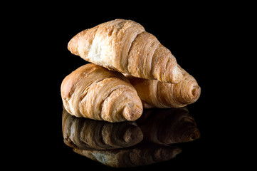 Croissants on black reflective background.