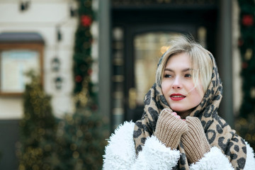 Fashionable model wears coat and knit scarf posing at the city. Space for text