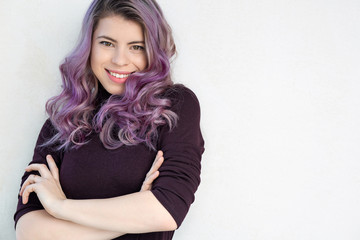 Fototapeta premium Adorable young woman with wavy purple hair and natural makeup looking to you. Space for text