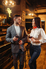 Man and woman drinks red wine at bar counter