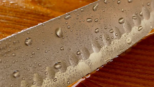 Chef's knife close-up. Knife santoku. blade blade. Drops of water flow down the blade of a knife. Cut vegetables. Cook lunch. Reflection of cold weapons.