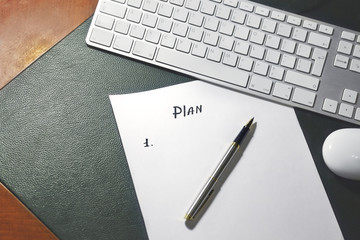 New planning Concept (sequence of items written by pen on white sheet of paper), on wooden table with green leather cover. White modern keyboard on background. Close up, copy space.