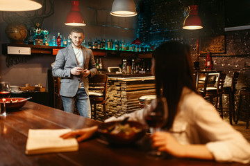 Man lovingly looks on woman at wooden bar counter