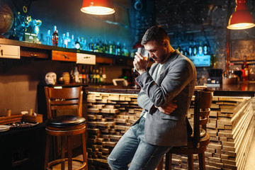 Sad man with glass at wooden bar counter