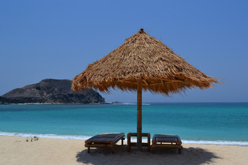 lonely beach with beach chairs and umbrella made of wood