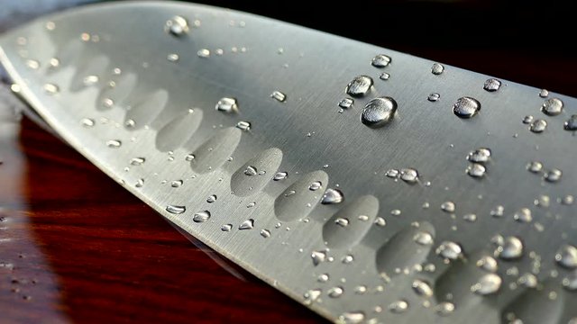 Chef's knife close-up. Knife santoku. blade blade. Drops of water flow down the blade of a knife. Cut vegetables. Cook lunch. Reflection of cold weapons.