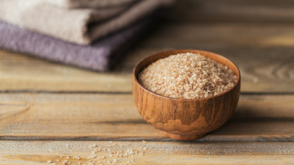 Sea salt and colorful towels on rustic wooden background