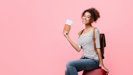 Excited african-american woman holding passport with tickets